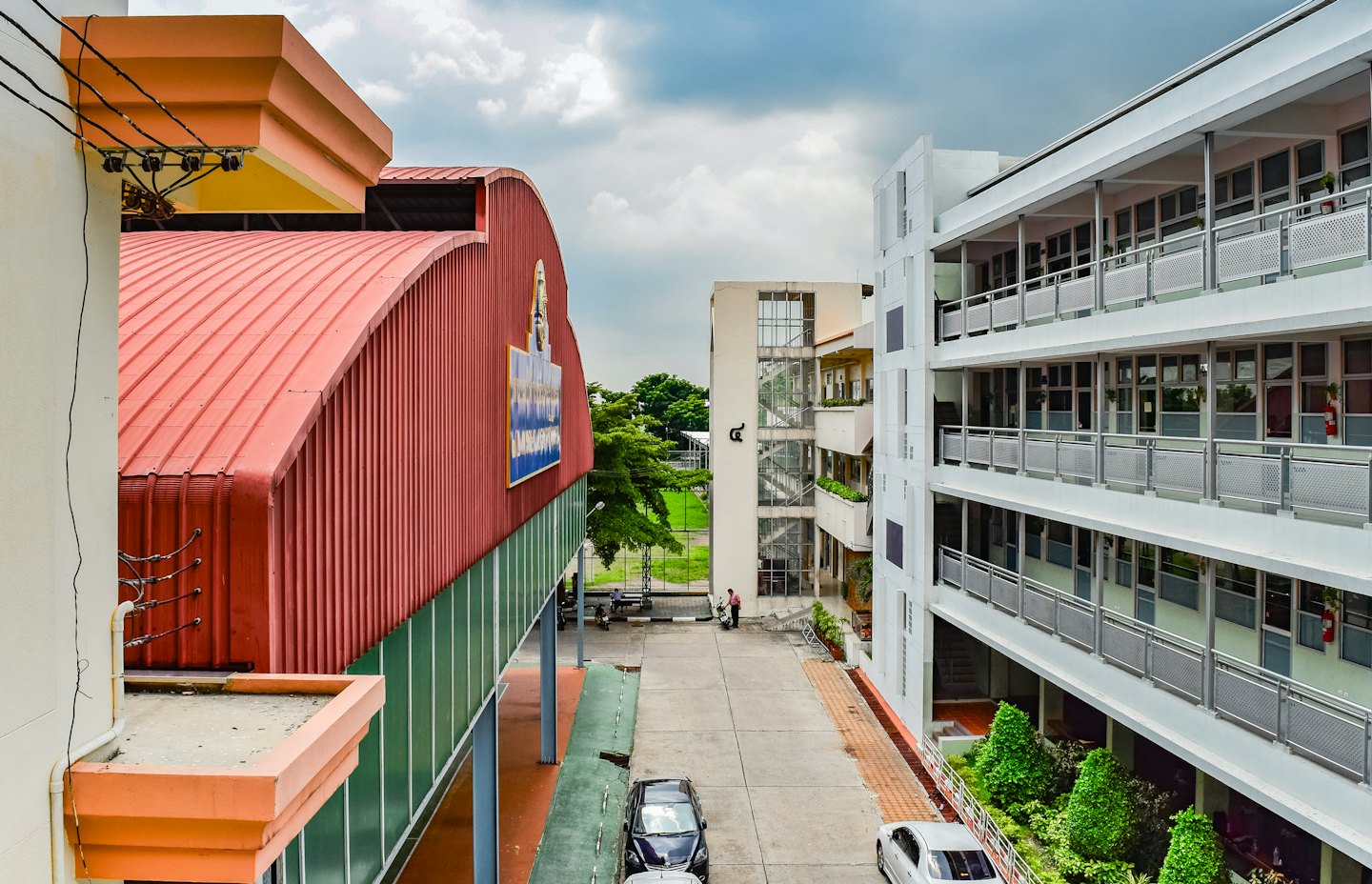 Gedung kampus dengan gerbang merah dan balkon putih.