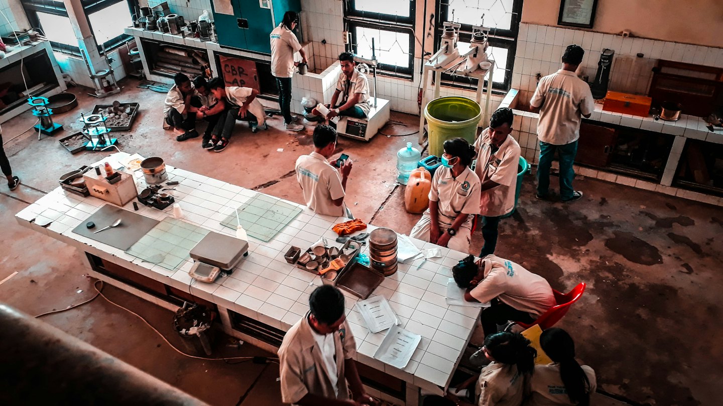 Mahasiswa bekerja dengan peralatan ilmiah di laboratorium pengujian material.