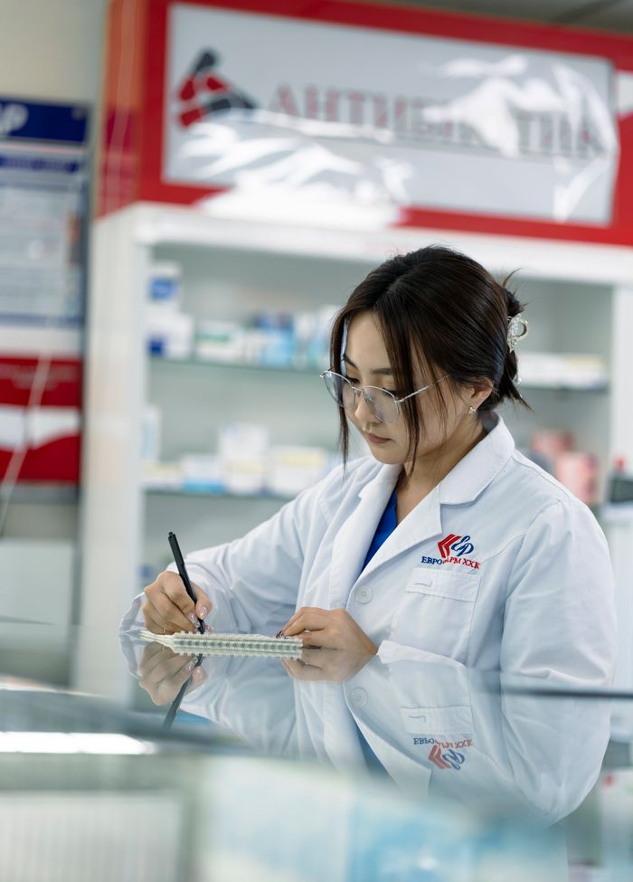 About Female pharmacist taking notes in a pharmacy environment.
